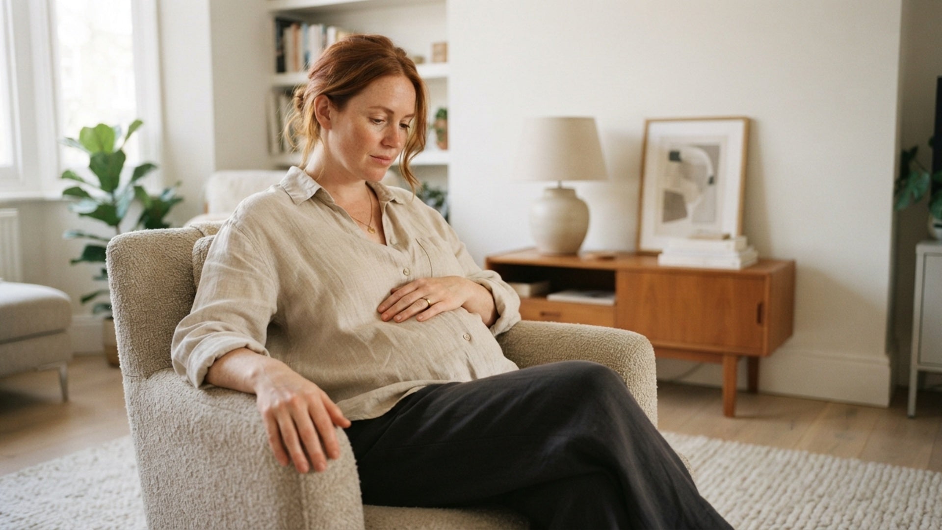 Woman mid 30s visibly pregnant at home